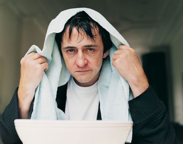 Sick man holding towel over his head