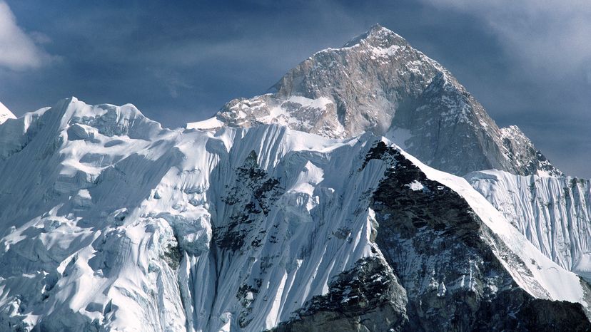 Lower pressure at higher altitudes causes the temperature to be colder on top of a mountain than at sea level. Pictured is Mount Everest behind the mountain of Nuptse. Education Images/UIG via Getty Images