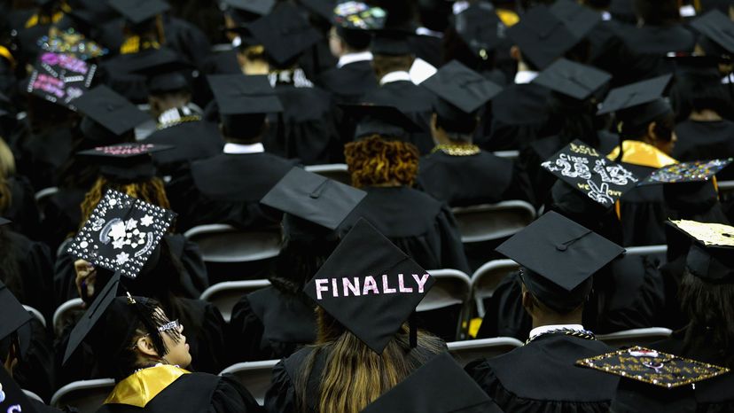 鲍伊州立大学的毕业生在他们的学士帽上写着信息＂width=