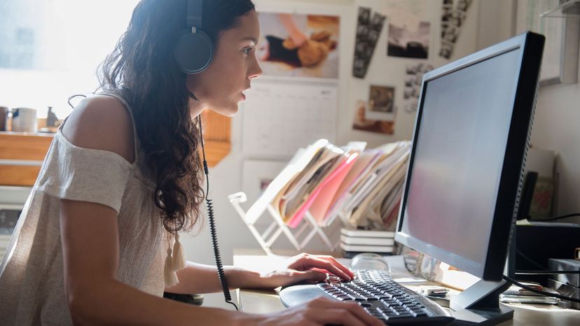 Hispanic woman listening to computer with headphones