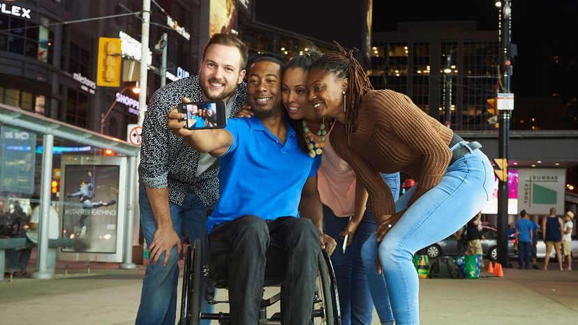 man in wheelchair with friends taking selfie