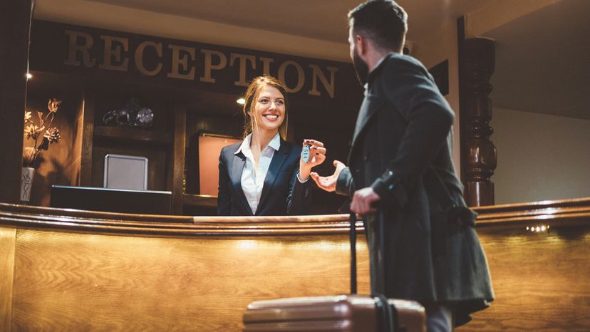 Man just arriving in hotel and receiving keys from his room after check-in