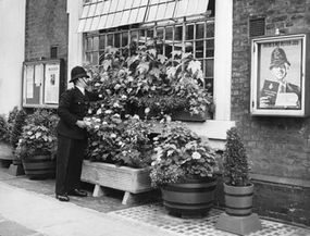 A policeman tends the window boxes at the front of Gerald Road Police Station in London.