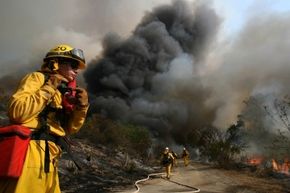 Firefighter Elizabeth Ferolito keeps an eye on a controlled backfire in Irvine, California, set to protect homeowners as a wildfire rages. 