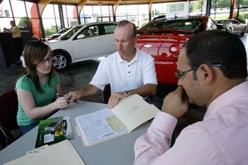 A customer signs the purchase contract in front of a salesman at Commonwealth Motors in Lawrence, Mass.