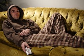 Man Sitting on a Couch with TV Remote in Hand