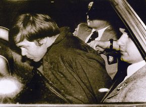 小约翰·欣克利。(L)被警察护送在华盛顿特区3月30日,1981年,在他被逮捕后拍摄然后重伤美国总统罗纳德·里根。”border=