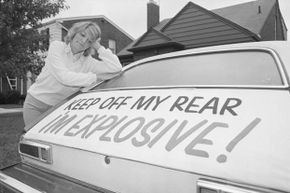 Patty Ramge appears dejected as she looks at her Ford Pinto where she put a sign on the rear of the automobile because of the firey accidents involving Pintos.