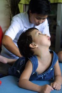 在泰国曼谷的一家治疗中心，一名患有脑瘫的泰国儿童在接受背部按摩以缓解肌肉痉挛时做出反应。＂border=