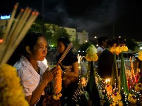 一个女人在2008年11月15日在曼谷的皇宫附近的火葬仪式上聚集并向已故的泰国公主加里亚尼·瓦达纳（Galyani Vadhana）致敬时祈祷。“border=