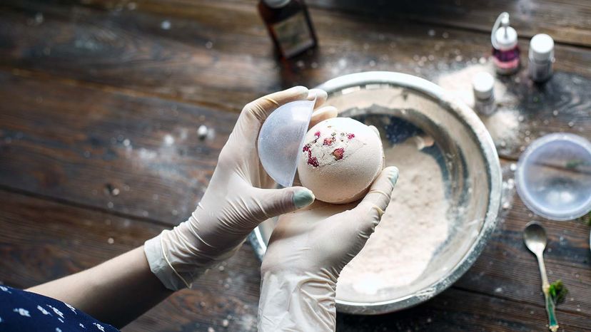 Person wearing gloves and making bath bombs using household ingredients.