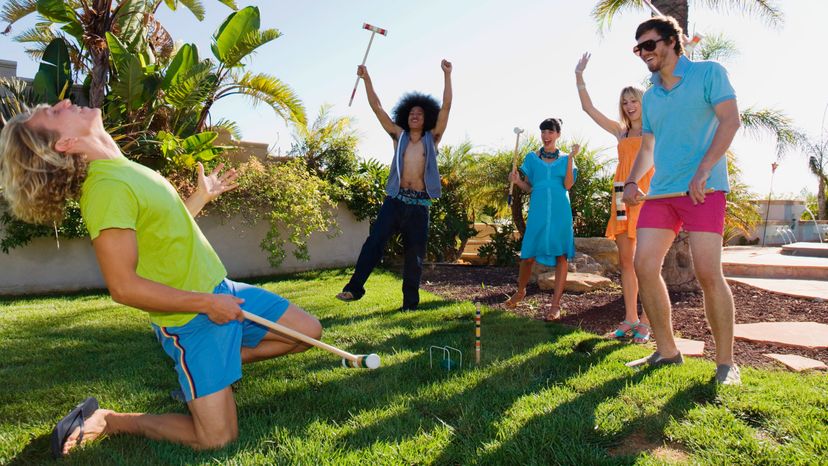 A group of happy friends playing croquet in the backyard.