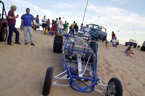 Steve Nickell, far left, and Terry Howe look over a dune buggy during a sunset cook-out on Nov. 22, 2002, at Imperial Sand Dunes Recreation Area near Glamis, Calif.