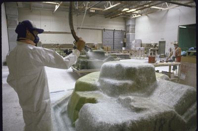 A worker sprays fiberglass over a spa mold 