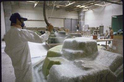 A worker sprays fiberglass over a spa mold