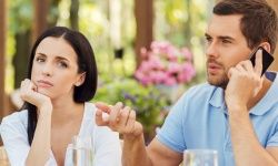 Man talking on cell phone while woman looks mad