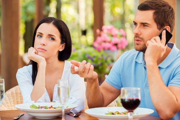 Man talking on cell phone while woman looks mad