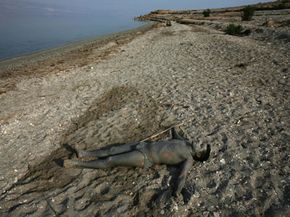一名以色列徒步旅行者在死海泥沐浴在阳光下。死海泥已经证明的治疗品质。”border=