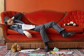 Businessman asleep on sofa.