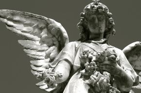 A statue of a crying angel in cemetery and flower.