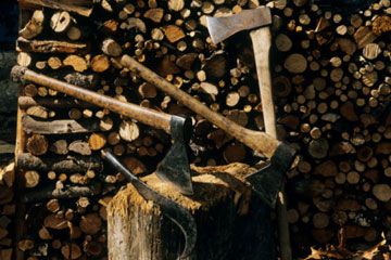 Industry workers wielding axe and hatchet to chop firewood.