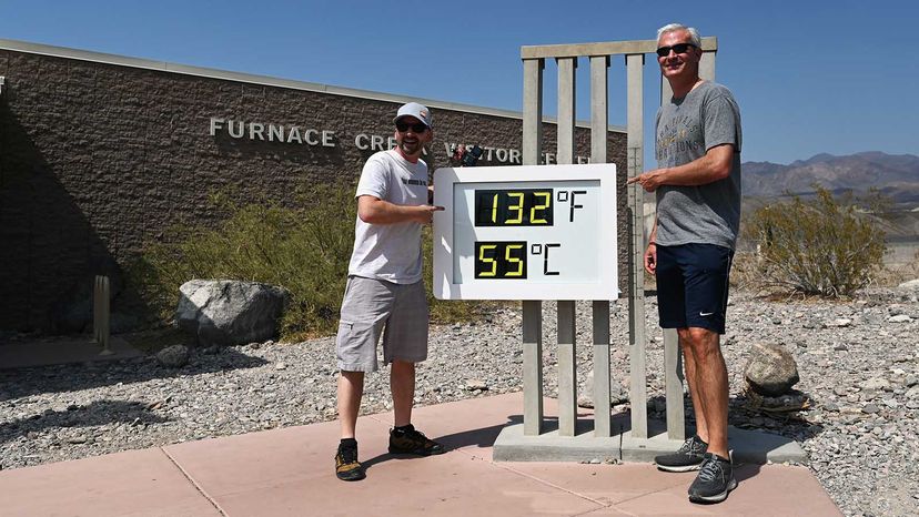 Men working outdoors, standing by sign.