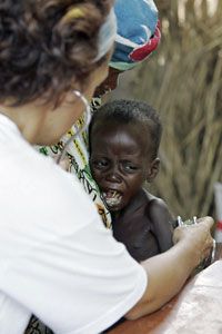 A nurse examines a malnourished child in Niger. Desertification contributes to the country's food shortages .
