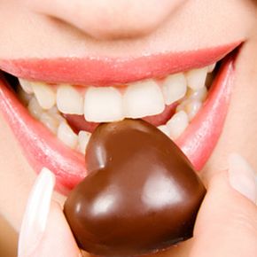 Closup of woman about to eat piece of chocolate.