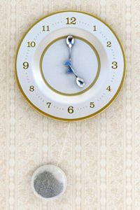 Concept image about teatime with clock shaped teaplate, spoons and a tea bag. High resolution 3D rendering.
