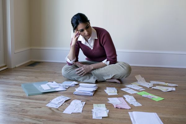 A woman looking at bills and receipts on the floor.