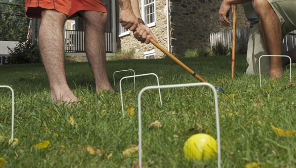 Two young men playing croquet