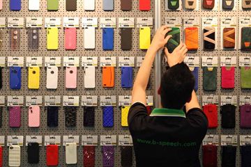 An employee arranges Apple iPhone cases at the D-Parts stand at the Internationale Funkausstellung (IFA) 2012 consumer electronics trade fair in Berlin, Germany.