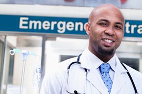 A doctor stands in front of a hospital exterior.