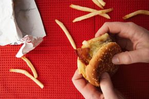 unattractive shot of french fries and man holding burger