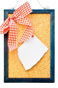 Cork board with pinned piece of paper and checked red and white ribbon.
