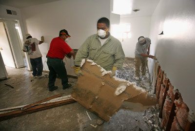 Workers remove drywall from damaged apartment.