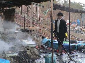 A man in Guiyu, China, heats a combination of nitric and hydrochloric acid, while inhaling acid fumes, chlorine and sulfur dioxide, without respiratory protection. Leftover acids and sludge are dumped in the river.“border=