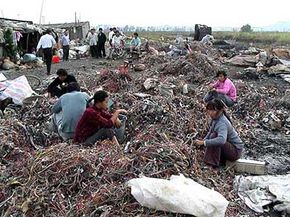 Women in Guiyu, China, sort wire that has been torn from discarded computers. The wires are sorted during the day and burned at night, releasing carcinogenic hydrocarbons and dioxins near areas where many families live.