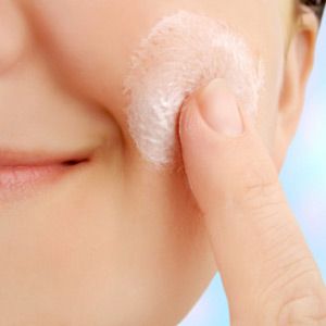 caucasian smiling woman applies moisturizer onto face