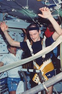 Astronaut G. David Low using a treadmill aboard the space shuttle Columbia as fellow crewmembers Daniel C. Brandenstein and James D. Wetherbee look on.