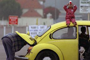 James L. Edward (left) checks the engine of his 1973 Volkswagen in Santa Monica, Calif., to make sure he doesn't have any trouble before making the return trip home to Alabama with his 2-year-old daughter Nahndi Malbrongh (on top of car).