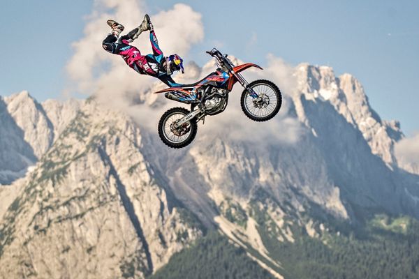 Luc Ackerman performs on a motorbike near a mountain