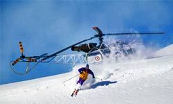 Helicopter speeds through snowy winter mountains.