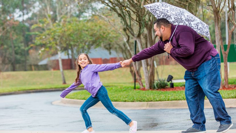 A girl and a father playing under the rain