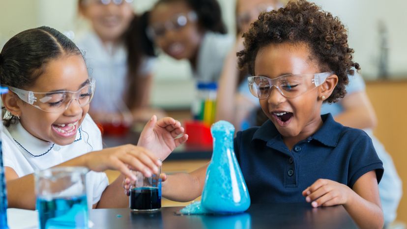 Diverse private school classmates are excited as foam overflows from beaker during chemistry experiment.