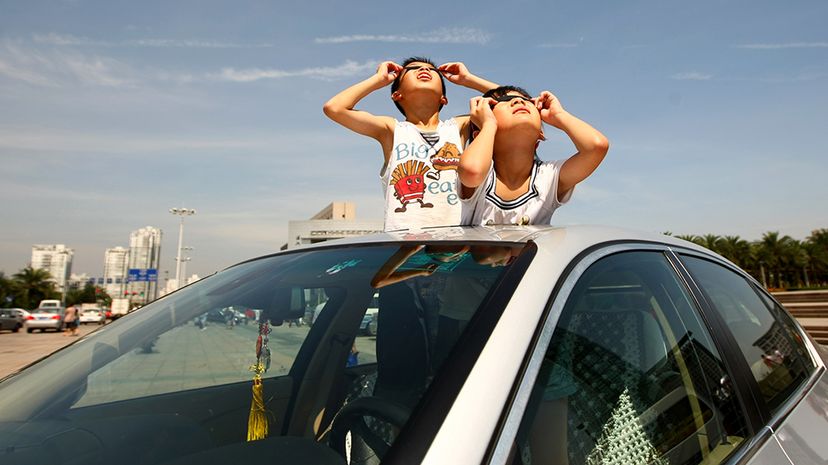 两个孩子观察日全食天窗的汽车7月22日,2009年,在温州,中国。本世纪最长的日全食太阳引发旅游亚洲发烧,紧张的基础设施。中国的照片/盖蒂图片社”width=