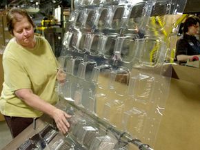 A quality control employee checks containers made from corn plastic as they come out of the forming machine.