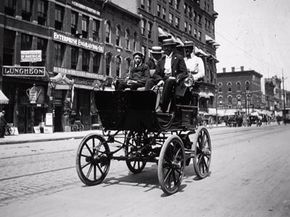 An early electric automobile, similar to the very first electric designs in its carriage-like appearance, travels down Hennepin Avenue in downtown Minneapolis in 1900.