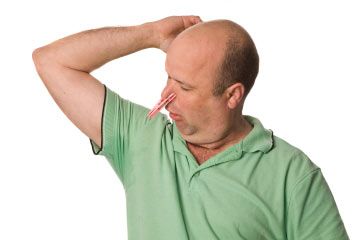 Man with sweaty under arms and clothes peg on nose.