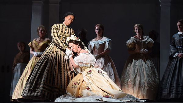 Women in dresses perform on stage in performance space.